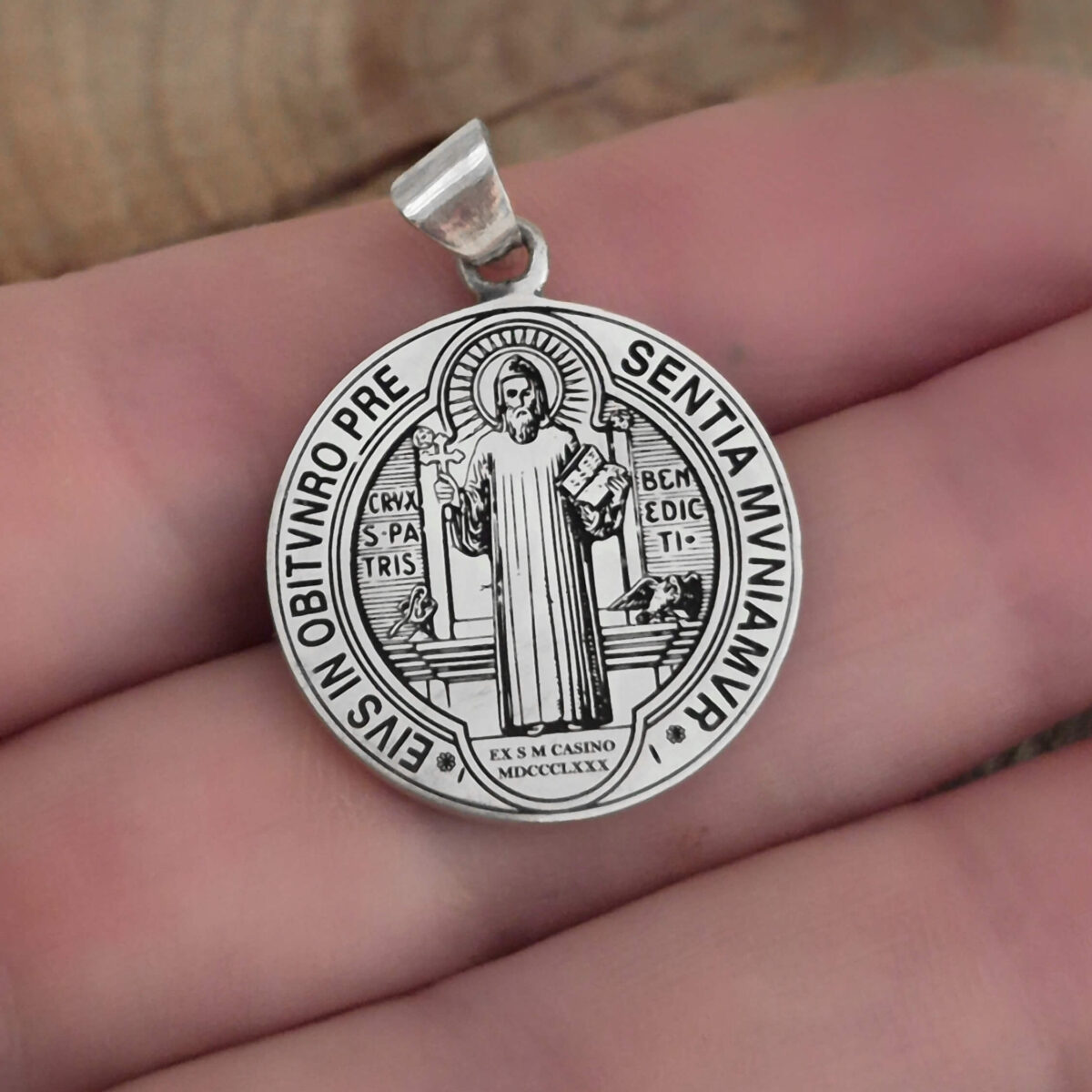 medalla san Benito en mano